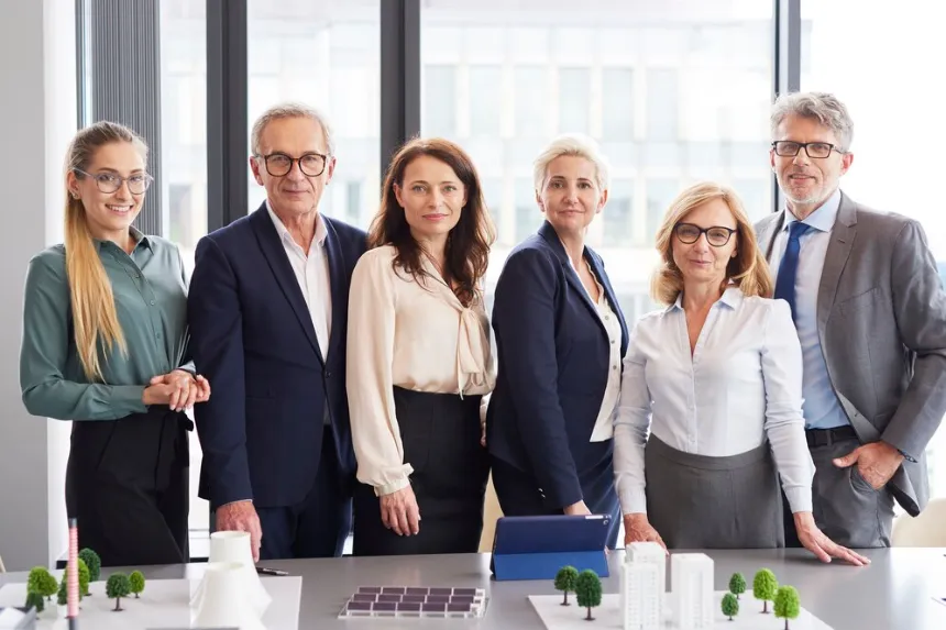 Executive team standing behind architectural models for business directory